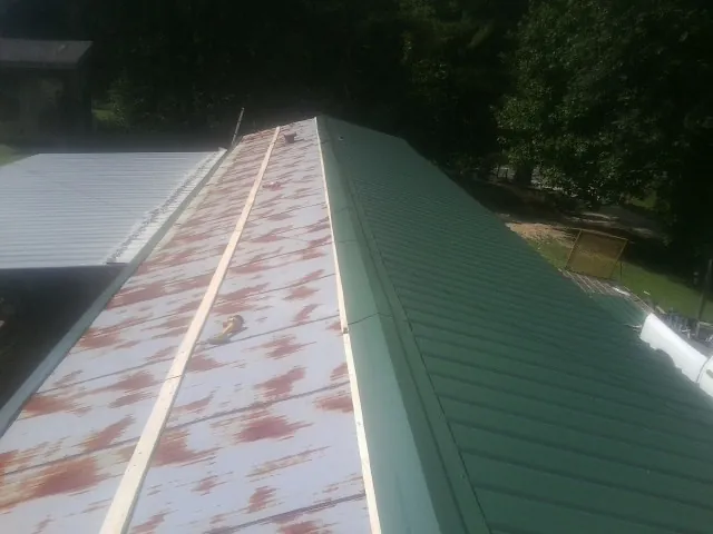 Old rusted panels beside newly installed green metal roofing — Wind Damage Roof Repair by Roofing Brothers in Randolph